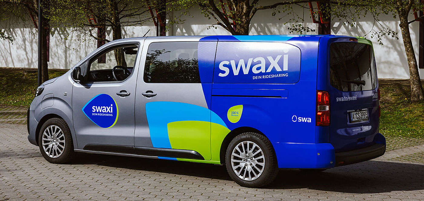 swaxi Transporter mit swaxi Branding an den Seite steht auf einem Parkplatz.