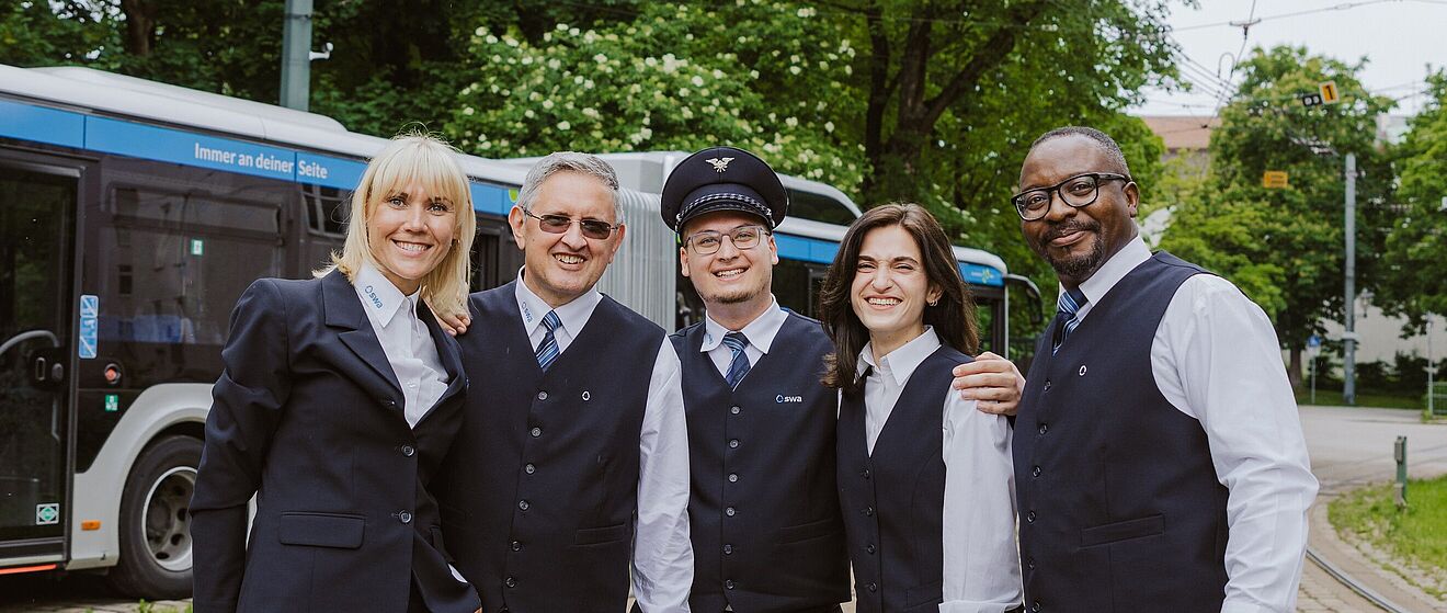 Fünf lachende Menschen in swa Uniform stehen draußen vor einem swa Bus