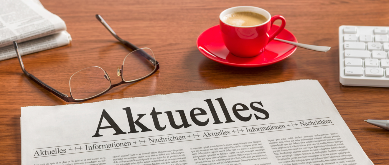 Tisch auf dem eine Zeitung eine Brille und eine Kaffeetasse liegt. Weiterverlinkung zu swa Presse