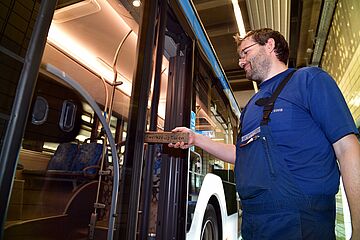 Mann steht vor Bus und prüft Türe