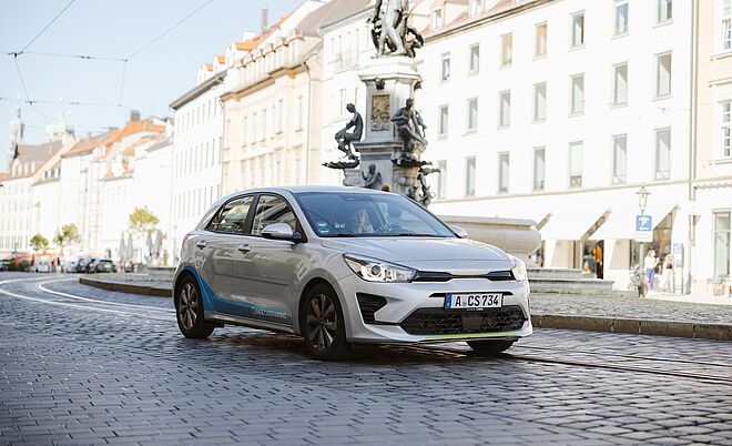Frau im swa Carsharing Auto fährt in der Maxstraße in Augsburg. Im Hintergrund ist ein Brunnen
